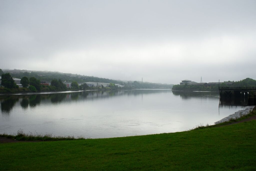 Serene misty riverbank scenery capturing calm waters and lush greenery in Newcastle upon Tyne.
