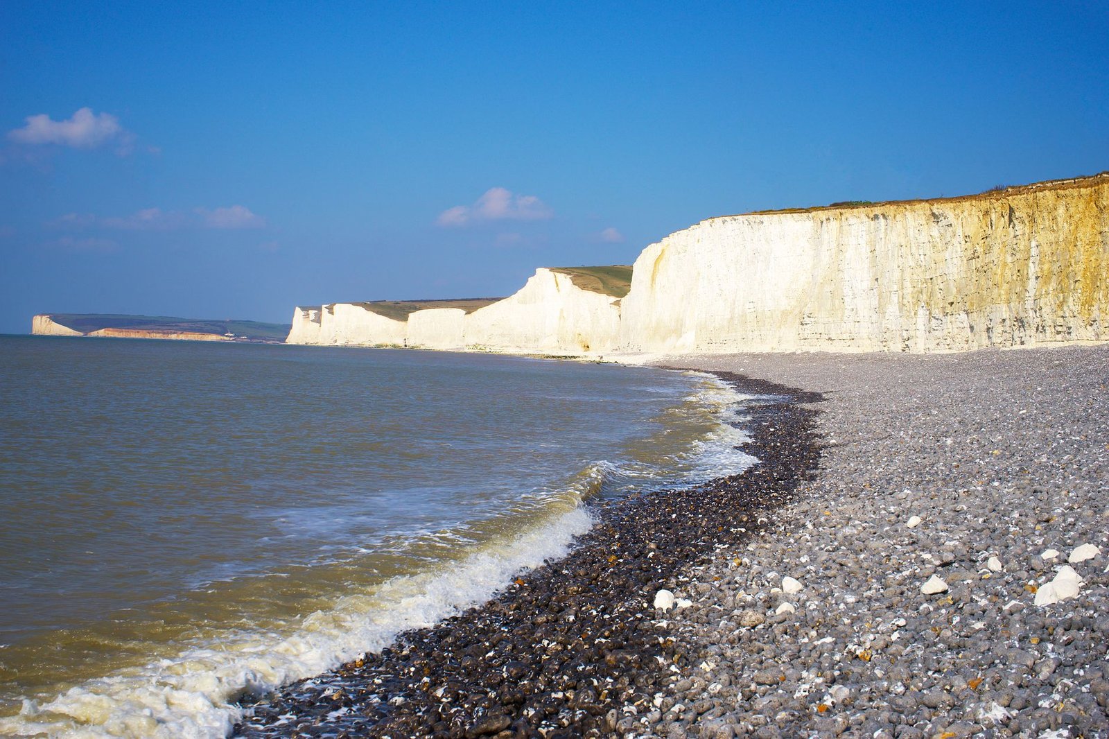 Beautiful view of the iconic white cliffs in Eastbourne, England with a rocky shore and calm sea.