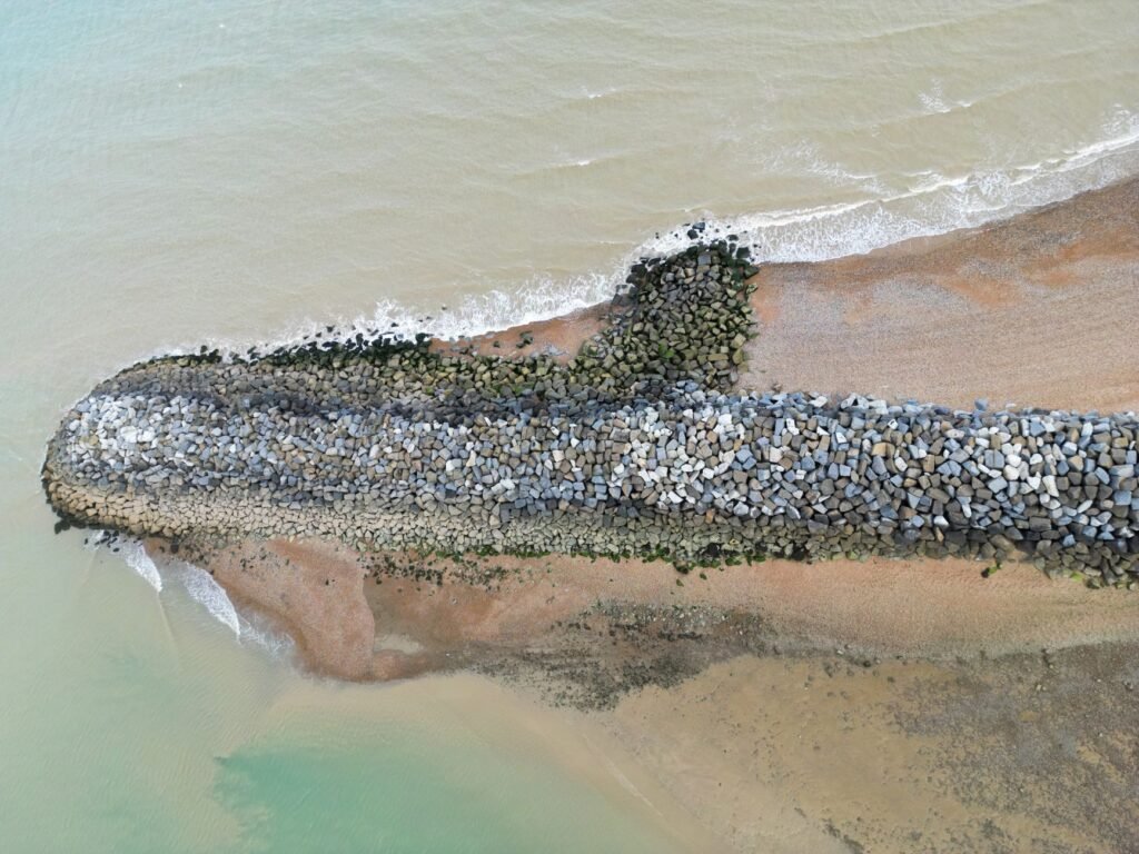 Aerial shot of a rocky jetty extending into the sea at Eastbourne, showing coastal details.