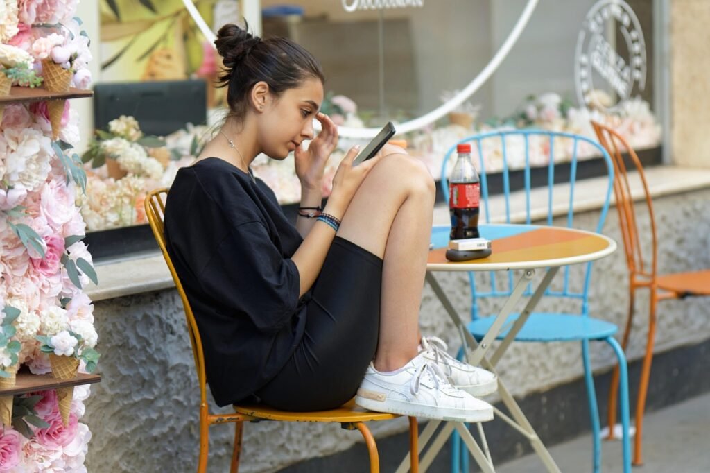girl, sitting, casual, crouched, outdoors, looking, smartphone, cafe, woman