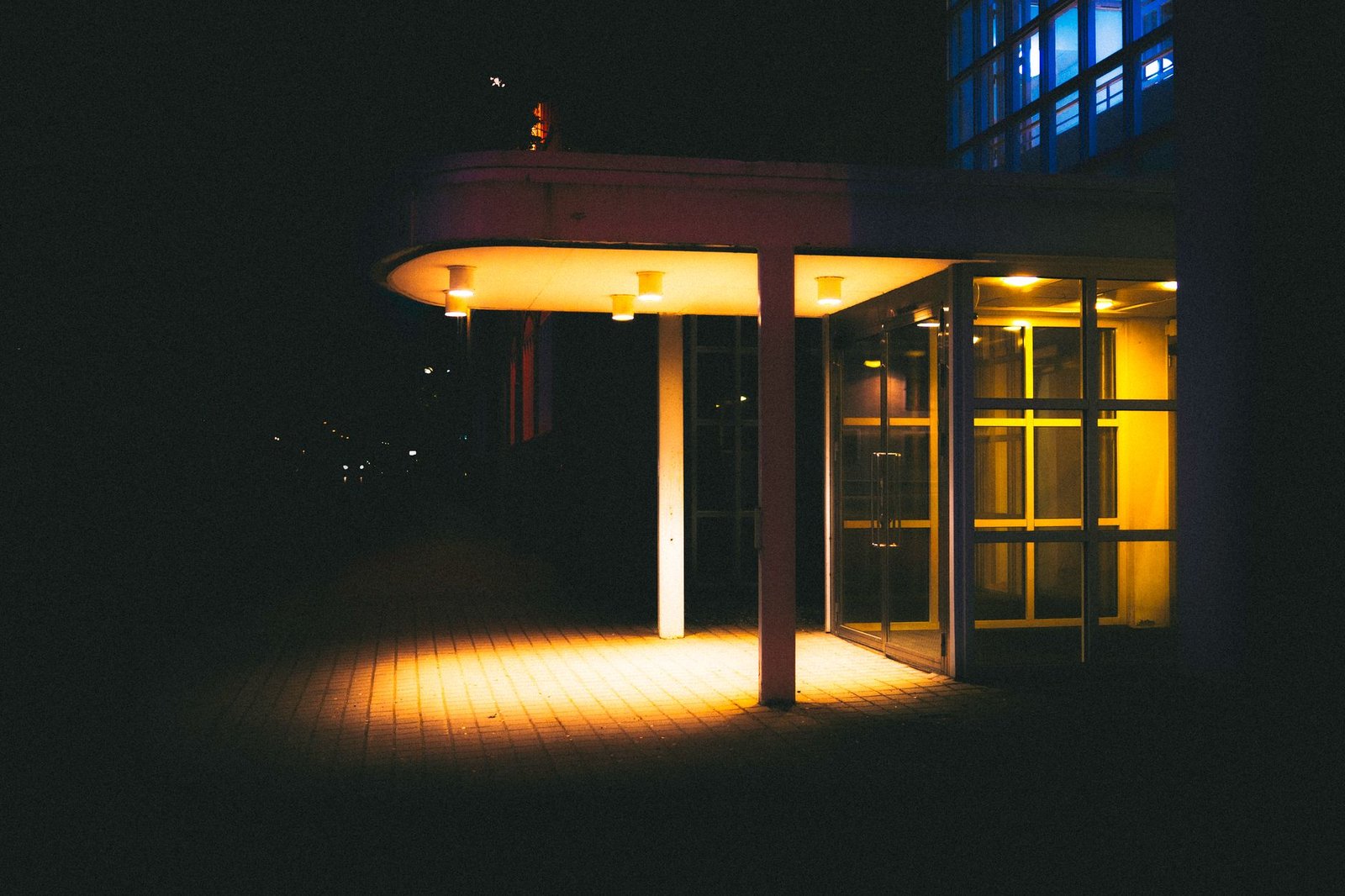 A nighttime photo of a modern building entrance with warm, glowing lights.