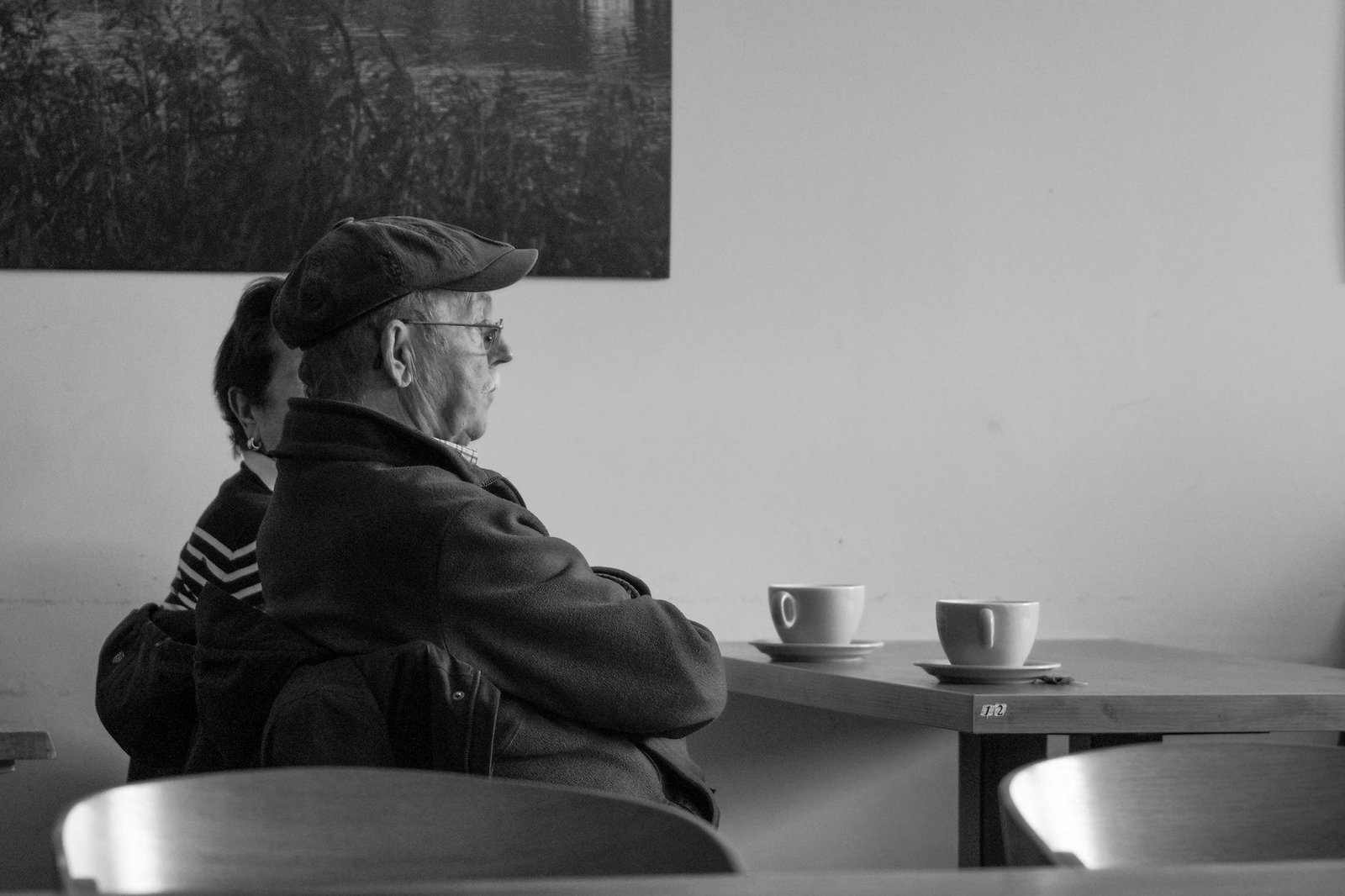 A senior couple sitting at a café, enjoying their leisure time with cups of coffee.