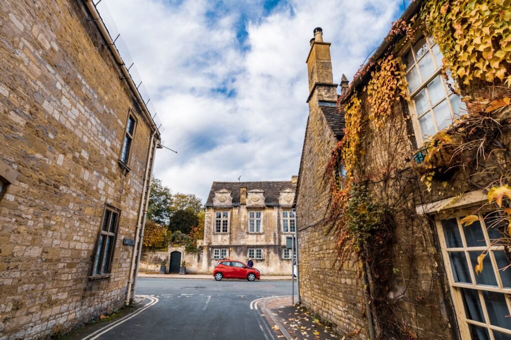 Explore the serene autumn charm of Burford's historic streets lined with ivy-covered stone houses.
