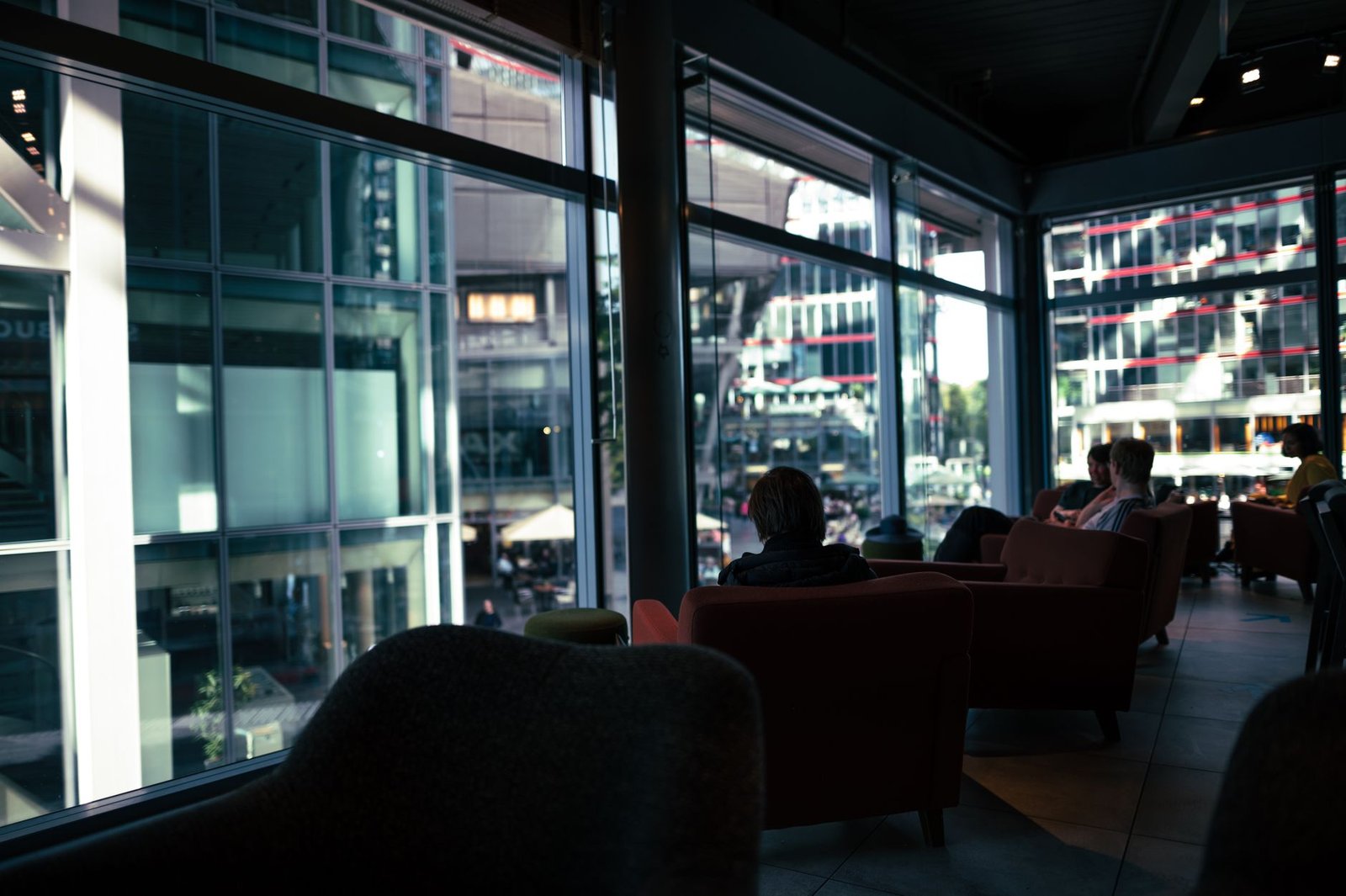 Relaxing scene inside a modern café with armchairs and large windows offering city views.