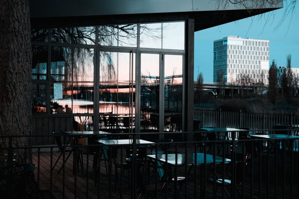 An outdoor cafe with glass reflections captures a stunning city skyline and sunset view.