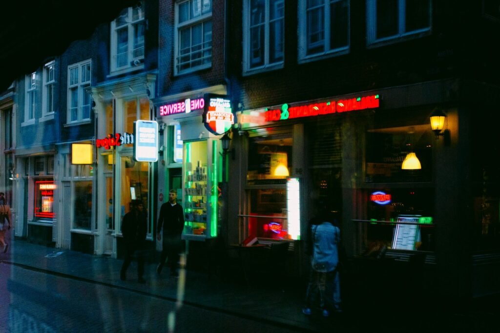 Urban night scene showcasing neon-lit storefronts and pedestrians on a bustling city street.