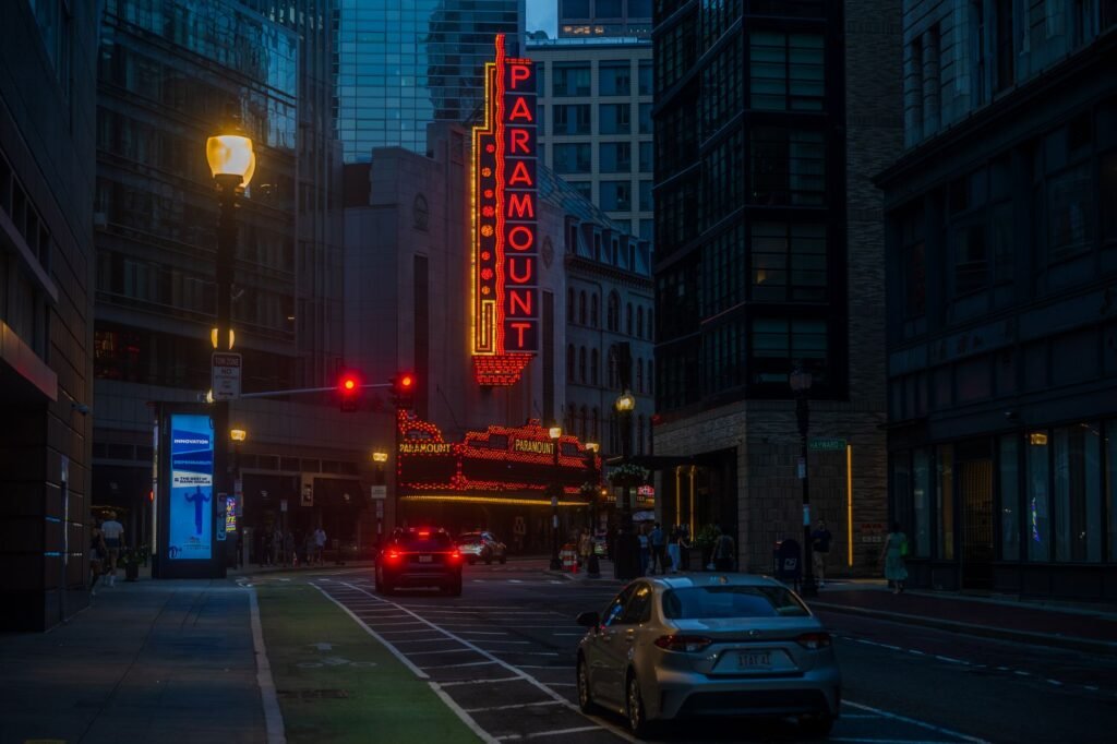 A lively street view of the illuminated Paramount Theatre in Boston at dusk, showcasing urban architecture.
