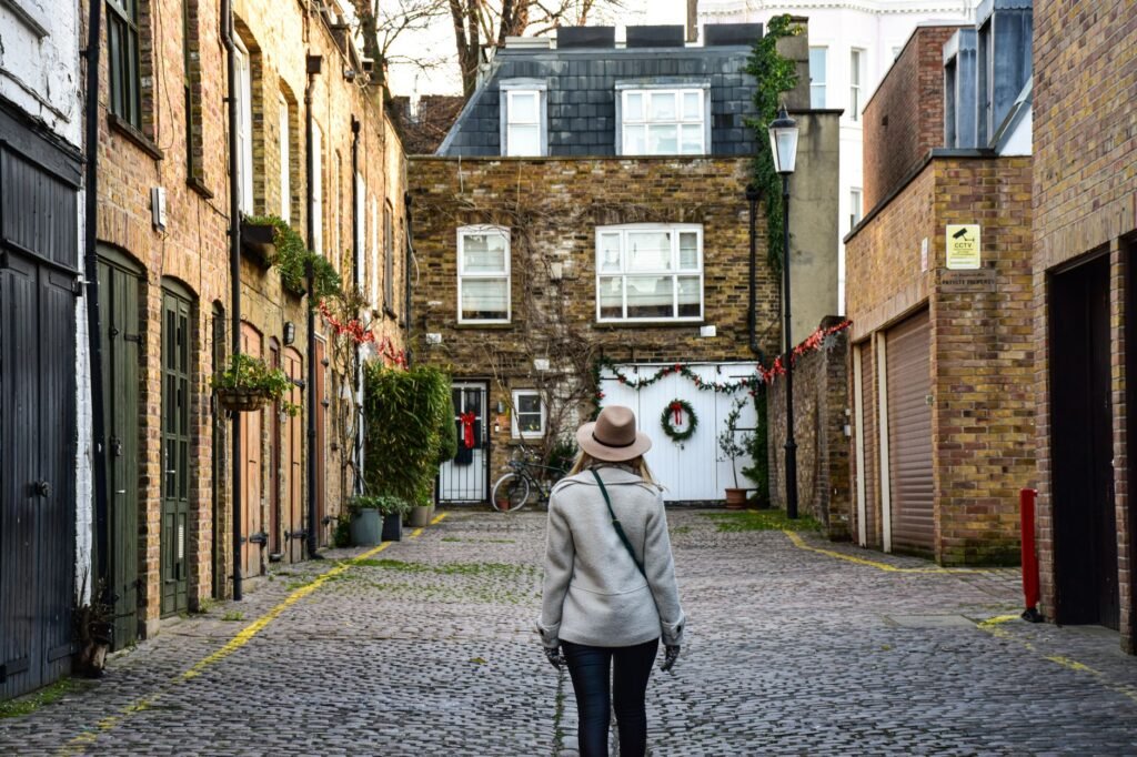 Cobblestone alley with a person walking in London, UK, showcasing charming historic architecture.