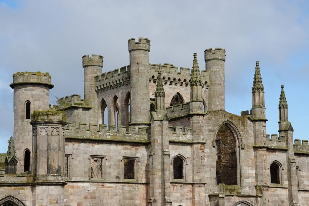 Medieval Gothic castle with towering structures and spires under a cloudy sky.