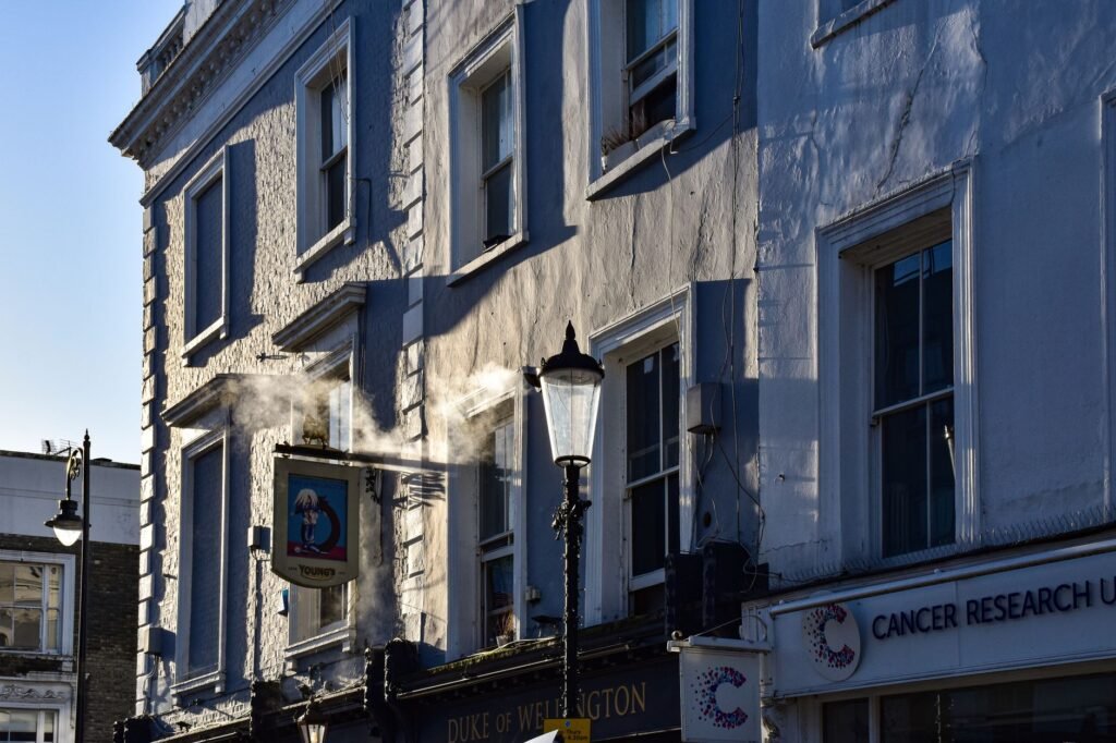Sunlit London street capturing the Duke of Wellington pub and Cancer Research UK.