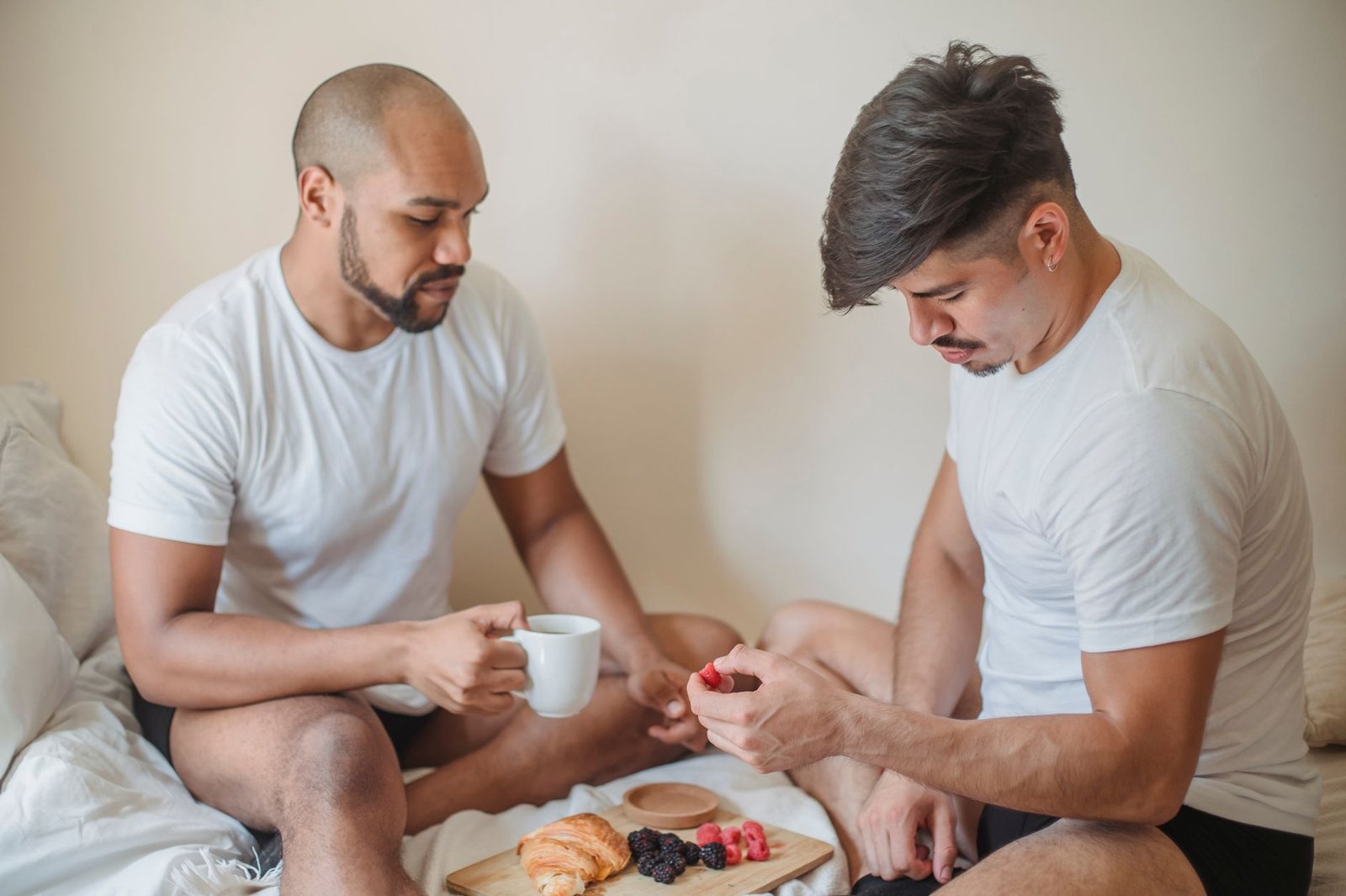 Couple enjoying a romantic breakfast in bed with croissants and berries.