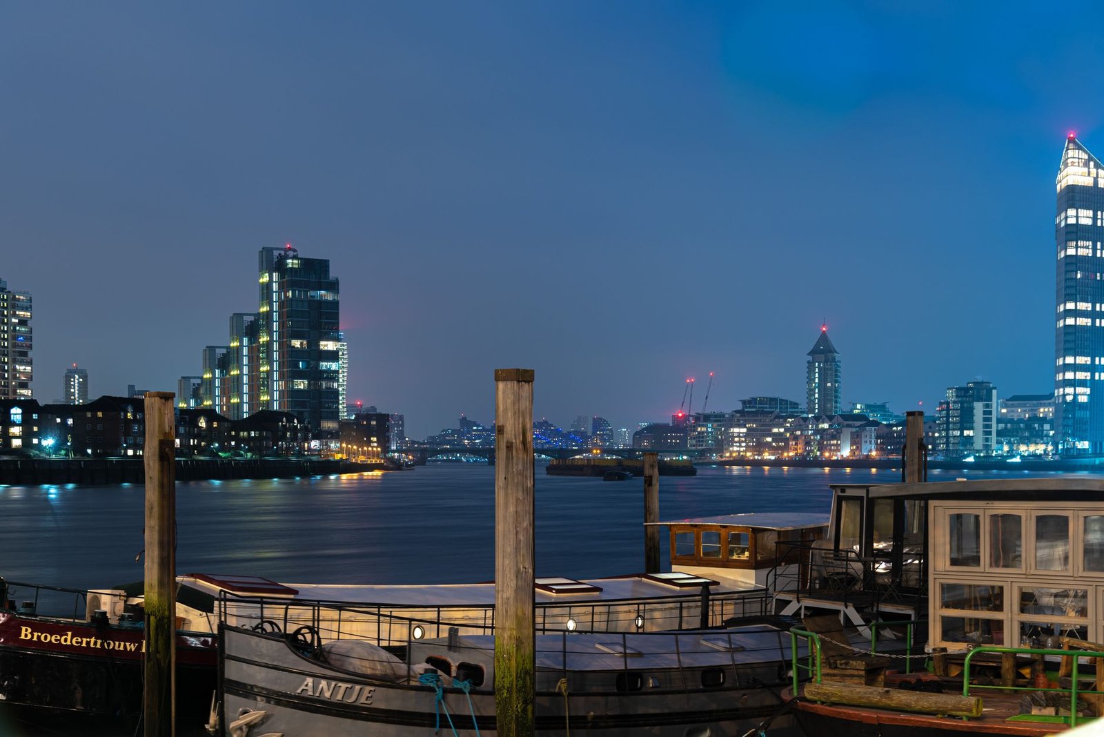 Scenic nighttime view of the River Thames with modern London skyline and boats.