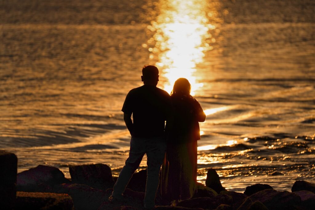 A couple enjoys a tranquil moment watching the sunrise over the ocean at Cove Island Park, Stamford.