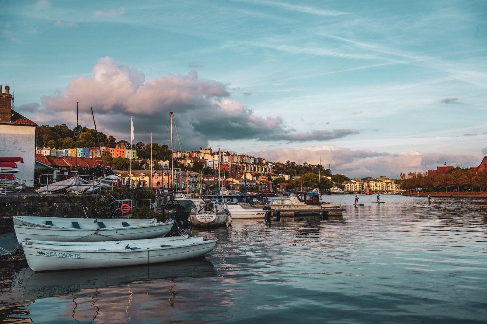 Scenic view of boats moored by a vibrant harborside town under a blue sky.