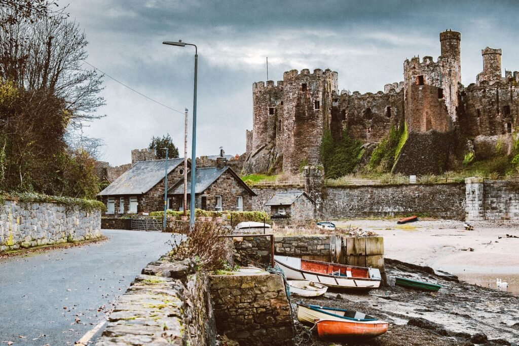 Scenic view of a historic medieval castle by the water with boats and stone buildings.
