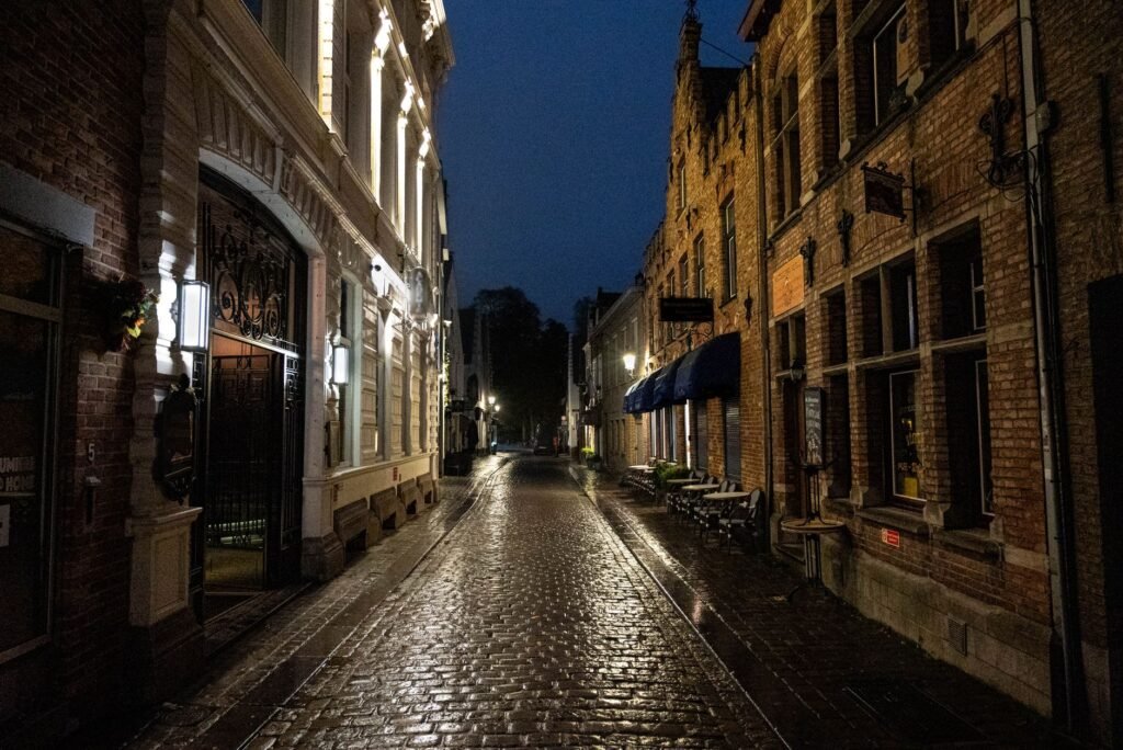 Cobblestone street in Bruges, Belgium, showcasing classic European architecture illuminated at night.