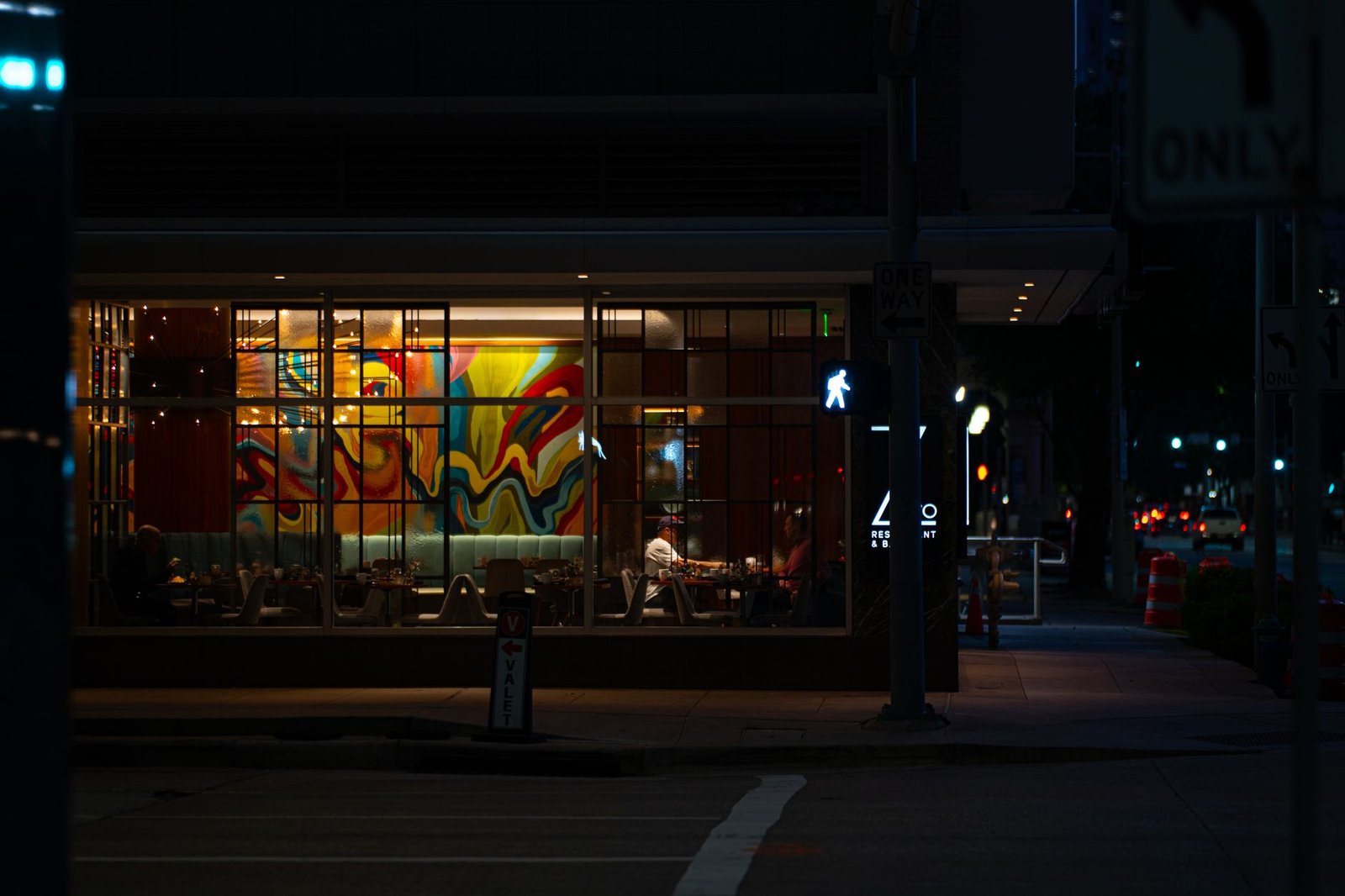 Captured at night, a vibrant Houston cafe with colorful mural through the window, evoking a lively yet calm evening vibe.