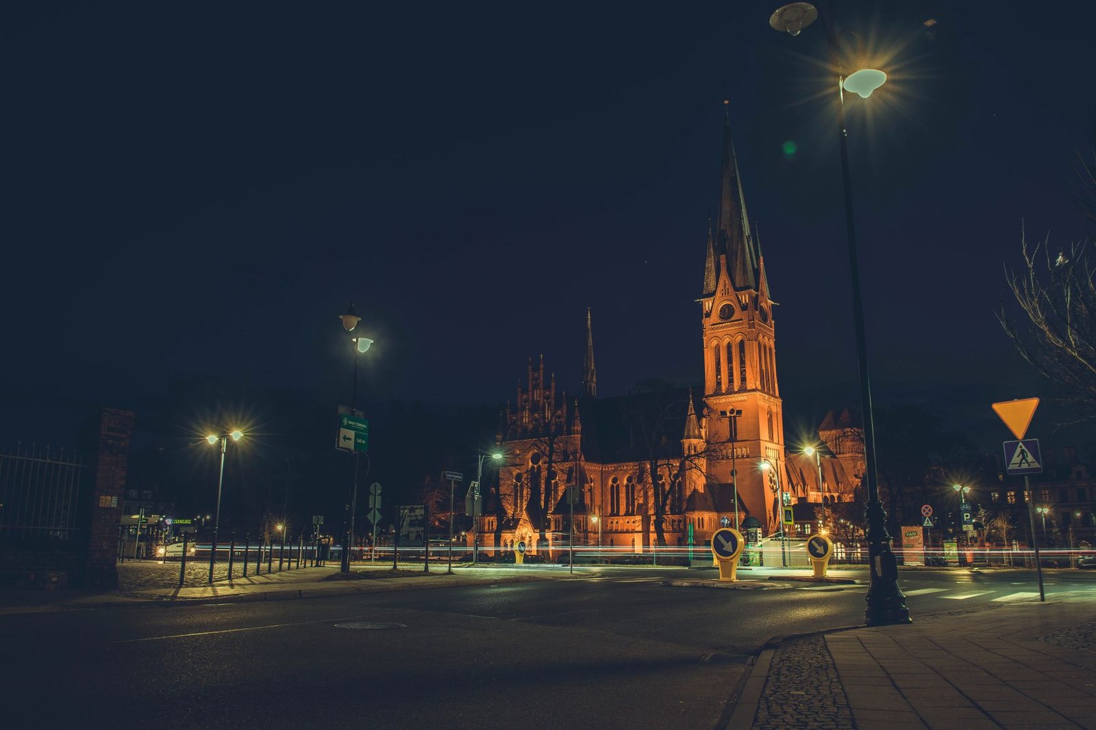 A stunning night scene of a well-lit Gothic church with city street elements.