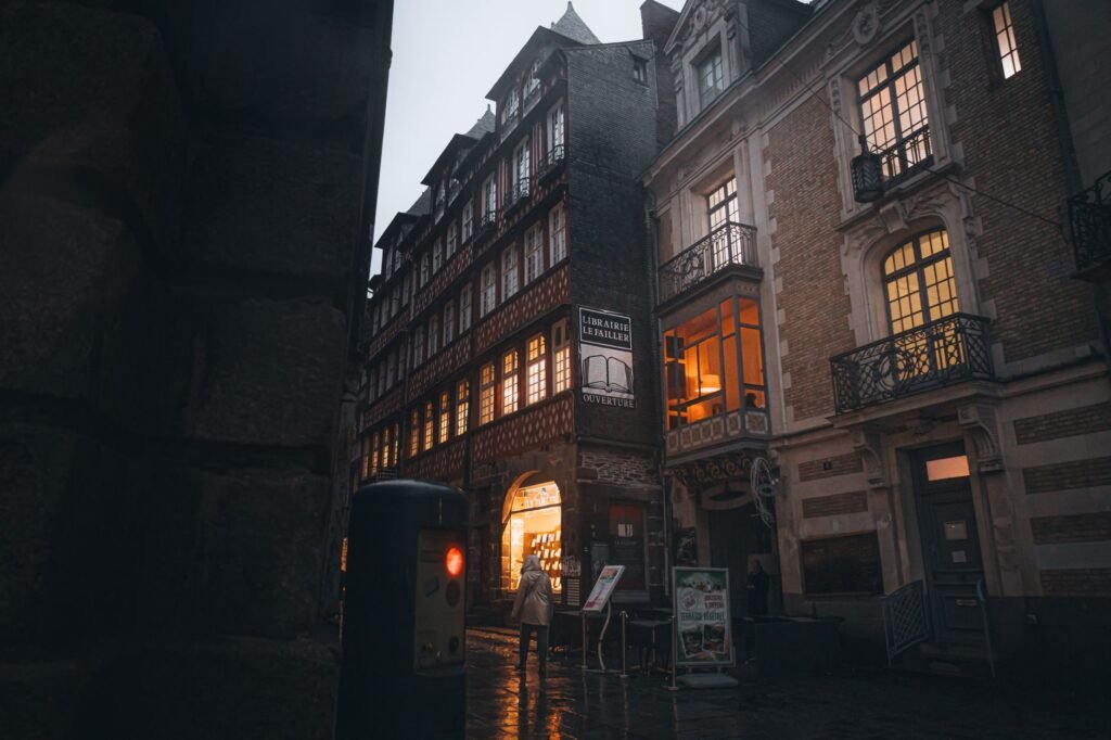 Nighttime view of stunning historic architecture and illuminated bookstore entrance in Rennes, France.