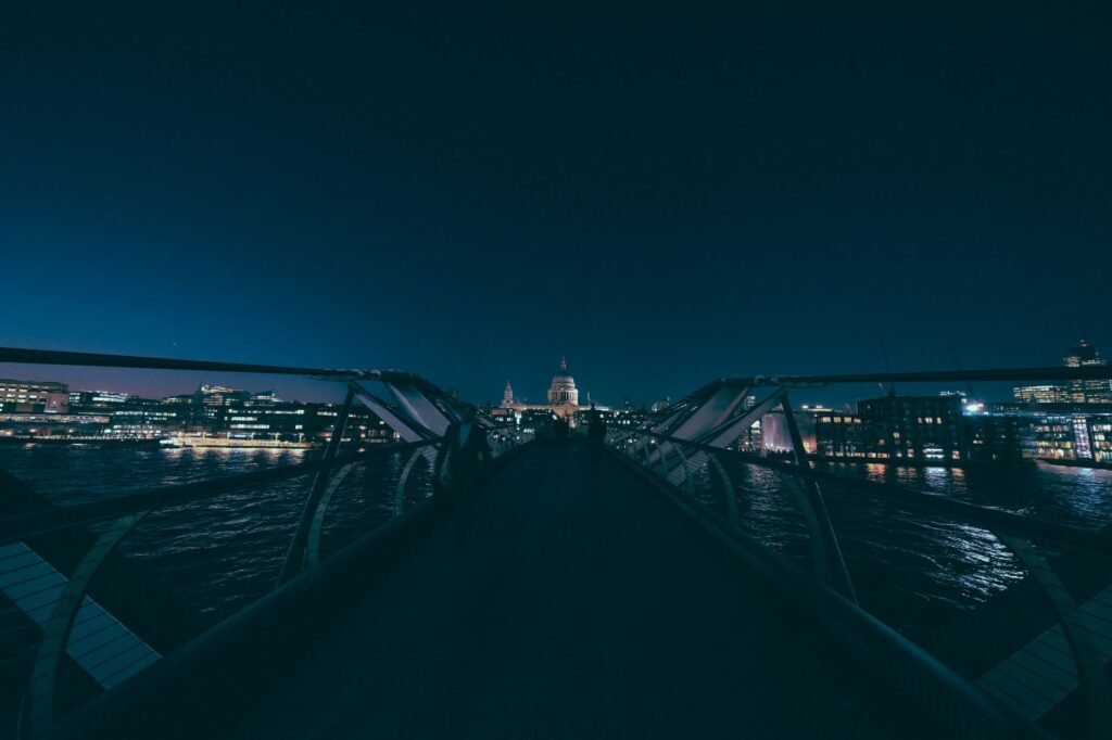 Stunning night view of Millennium Bridge leading to a city skyline illuminated by lights.