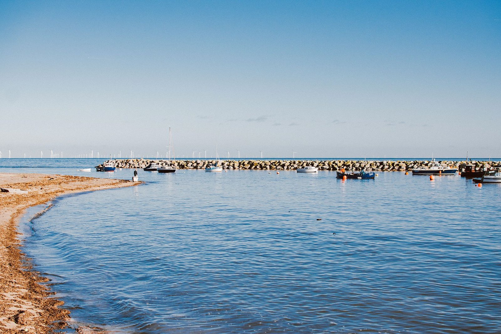 A serene coastal view of boats anchored at Rhos on Sea harbor in Wales.