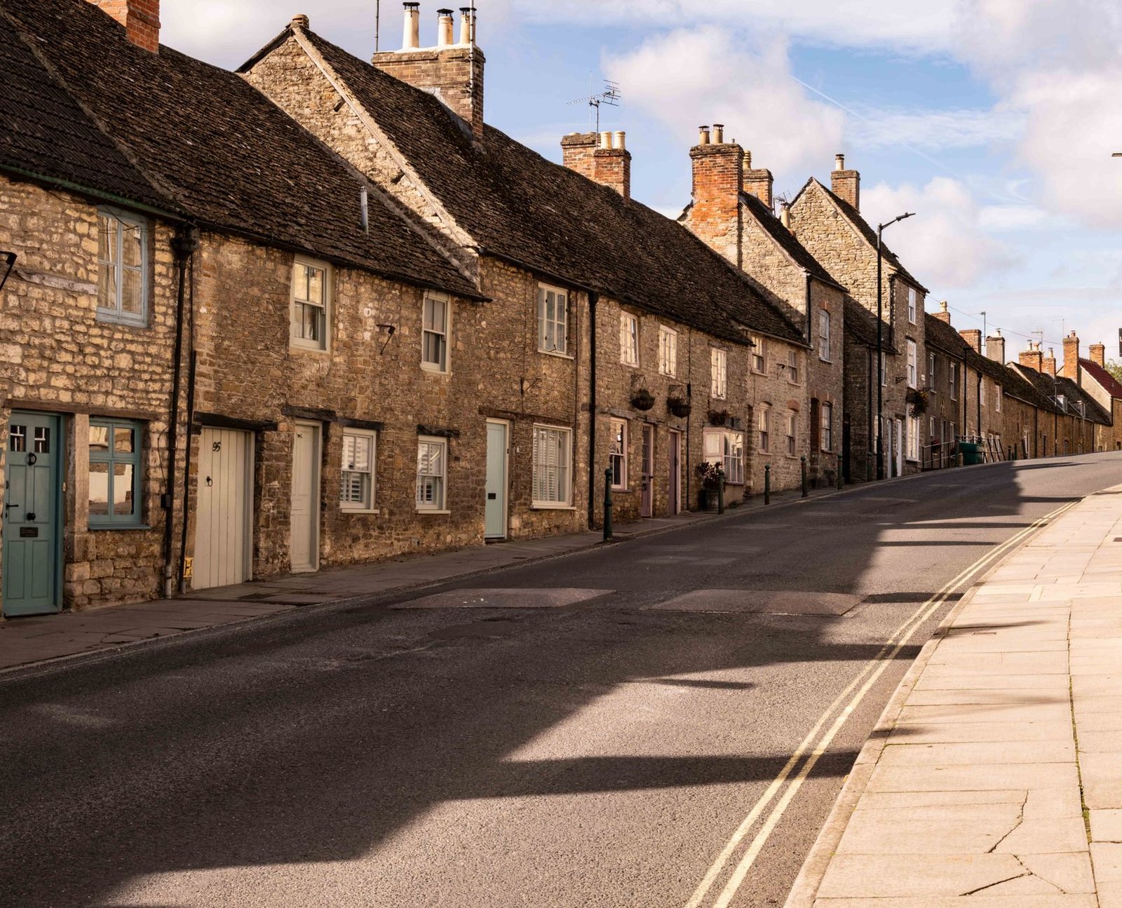 Charming stone cottages line a quiet street in a picturesque English village.