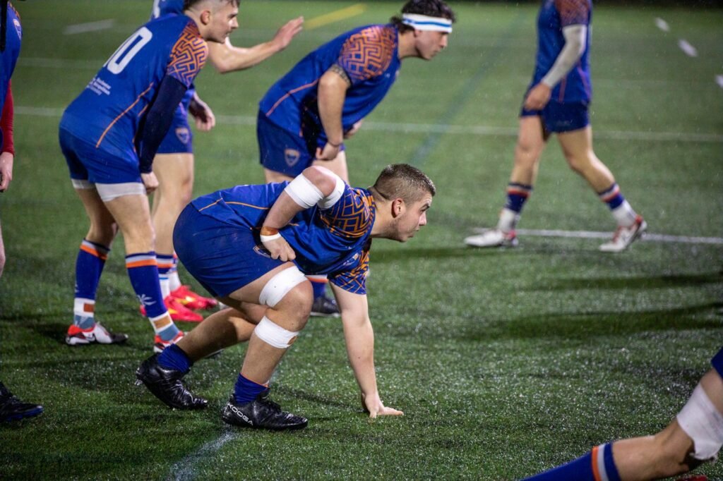 Rugby players in action during a match at night in Manchester.