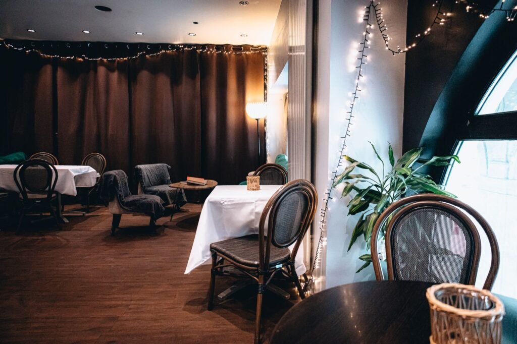 A warm and inviting indoor cafe setting with string lights and elegant table arrangements.