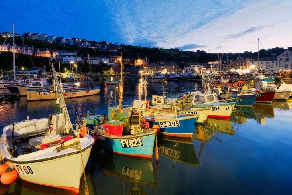 Beautiful evening at a harbor with colorful boats and illuminated buildings reflecting in the calm water.