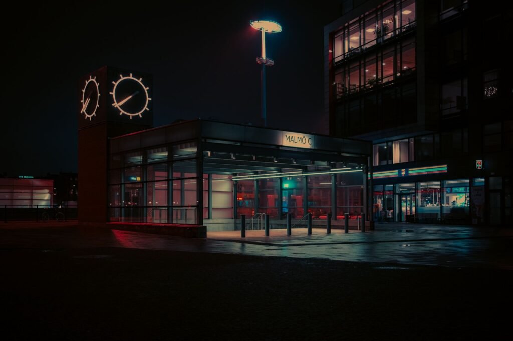 Atmospheric night view of Malmö C station with neon lights and reflections.