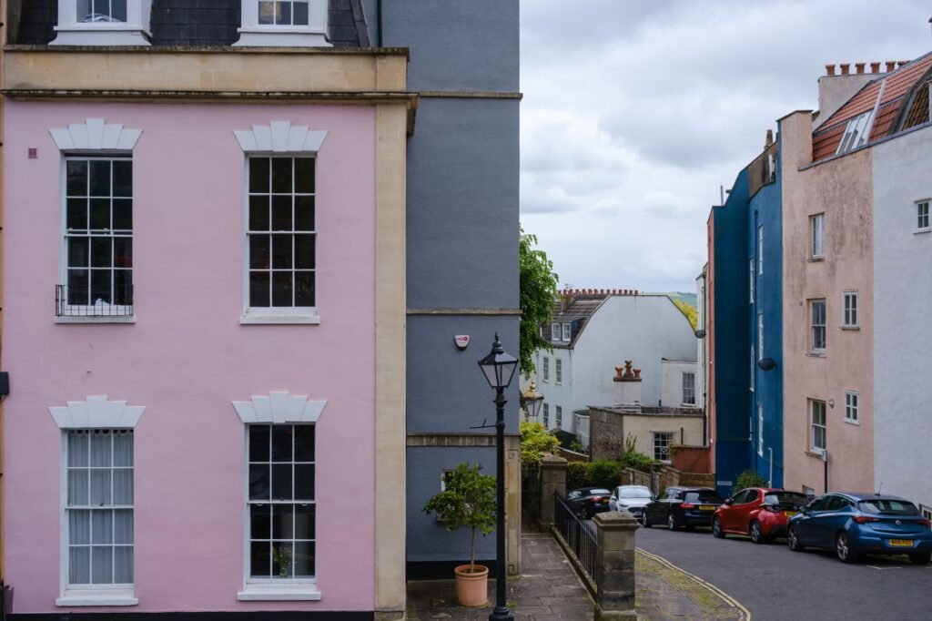 Colorful houses line a quiet urban street with parked cars and classic architecture.