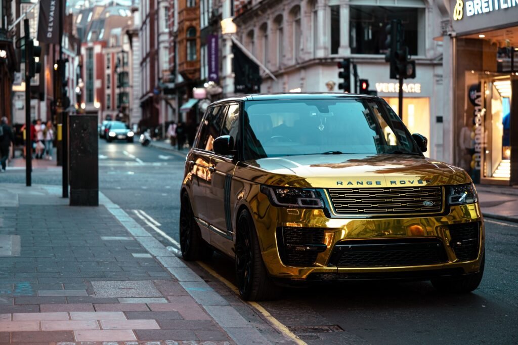 A luxurious gold Range Rover parked in a vibrant London street at dusk.