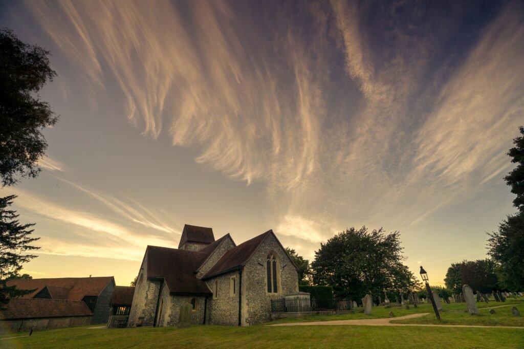 Beautiful sunset view of a historic church in Sarratt, England, surrounded by lush greenery.