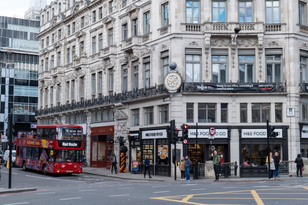 London street view with iconic double-decker bus at a bustling city intersection.