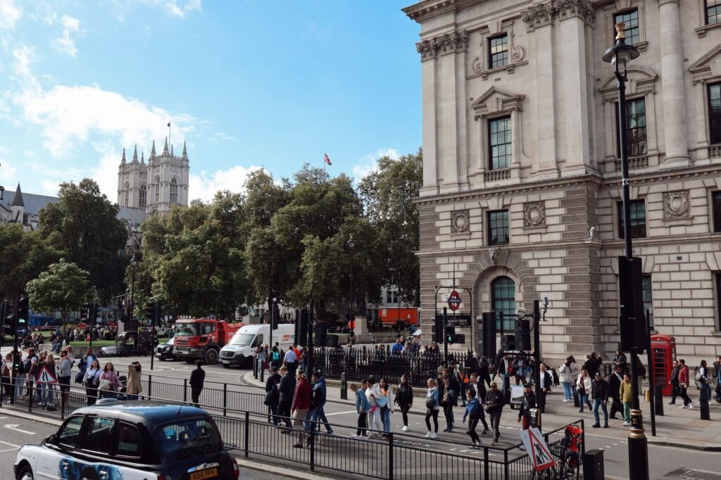 Vibrant scene of a busy London street with a view of Westminster Abbey and iconic red telephone booth.