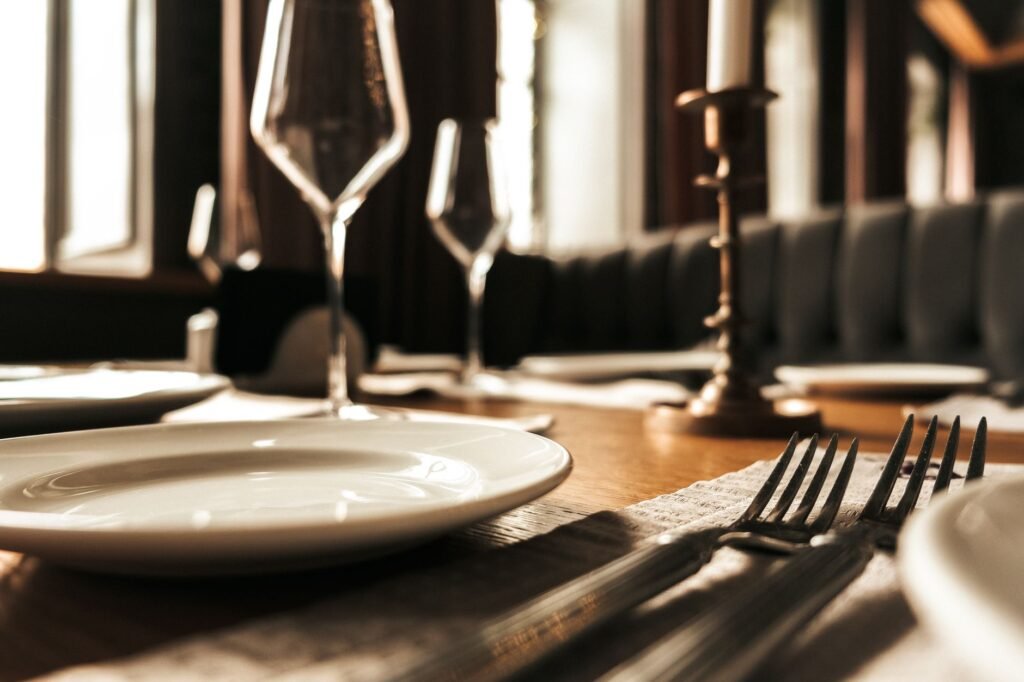 Close-up of a stylish table setting with plates and glasses in a warm, cozy restaurant.
