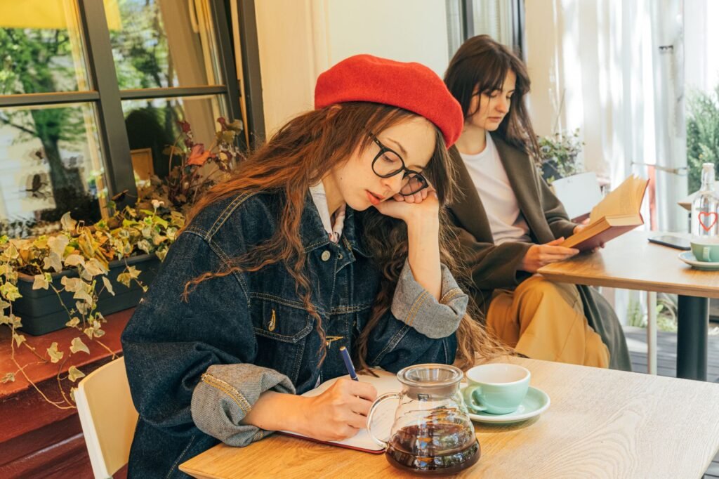 Two women engaged in reading and writing in a charming café. Perfect for lifestyle and coffee culture themes.
