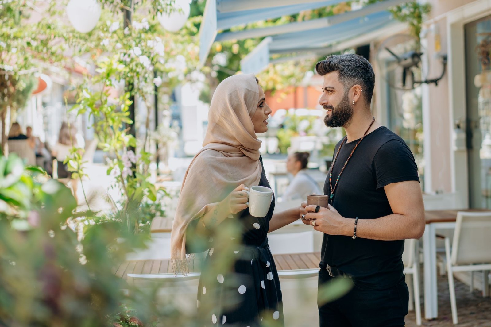A couple enjoying coffee outside a sunlit cafe, engaging in a lively conversation and sharing a joyful moment together.