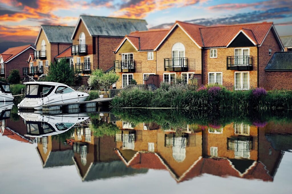 Picturesque riverside homes with colorful sunset reflection on a canal in the UK, capturing serene beauty.