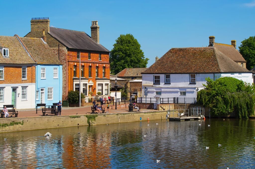 Historic English village with colorful houses reflecting on a serene river.
