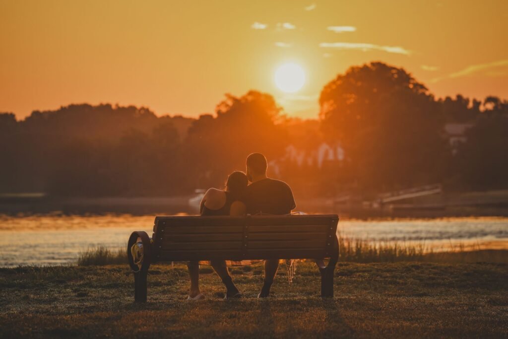 A couple embracing on a bench at Cove Island Park during a stunning sunset in Stamford, CT.