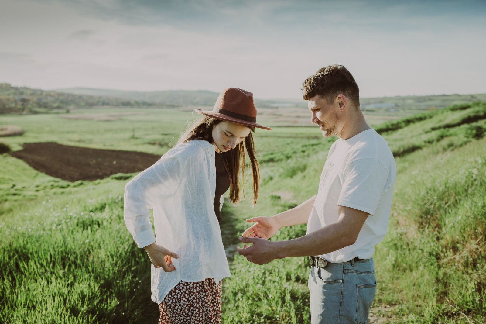 A couple enjoying a leisurely walk in the countryside on a sunny summer day, fostering romance and togetherness.