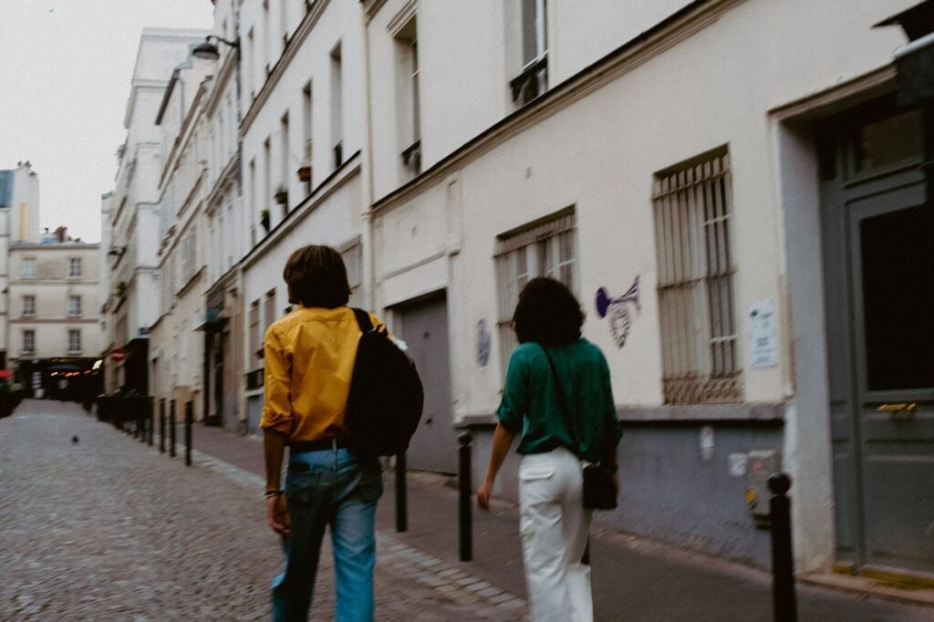Couple from behind walking through a cobblestone street in a European cityscape.