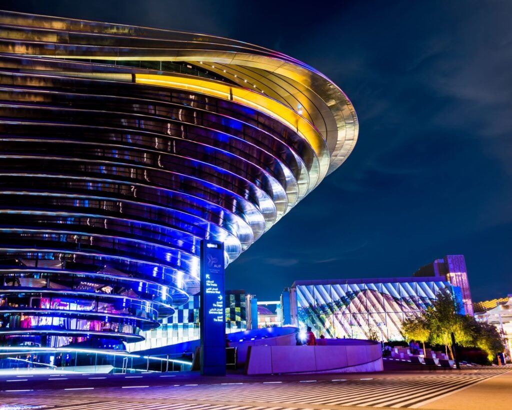 Vibrant night view of a futuristic building with colorful lighting and unique design.