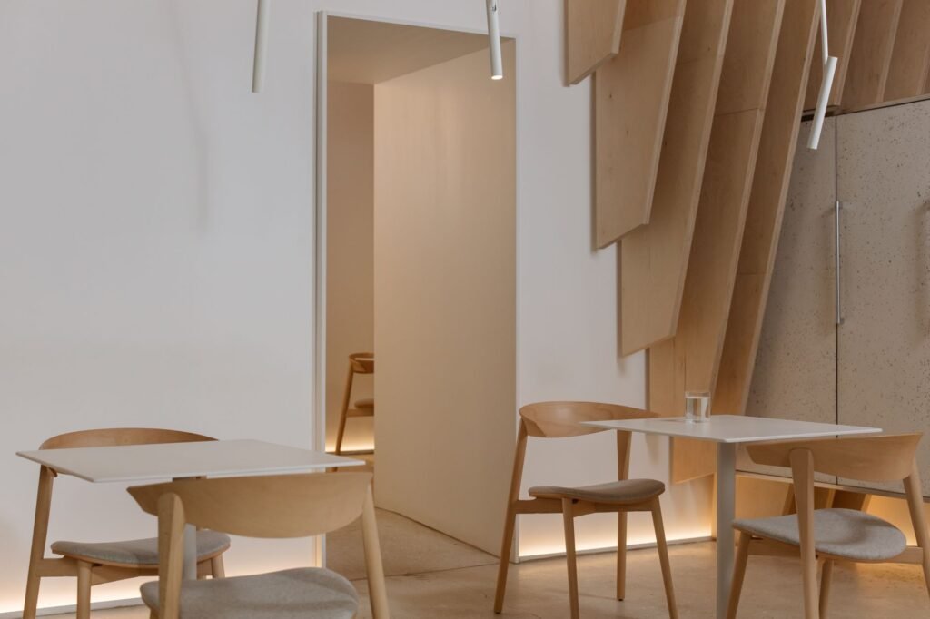 A serene minimalist room with wooden chairs and tables, showcasing modern interior design.
