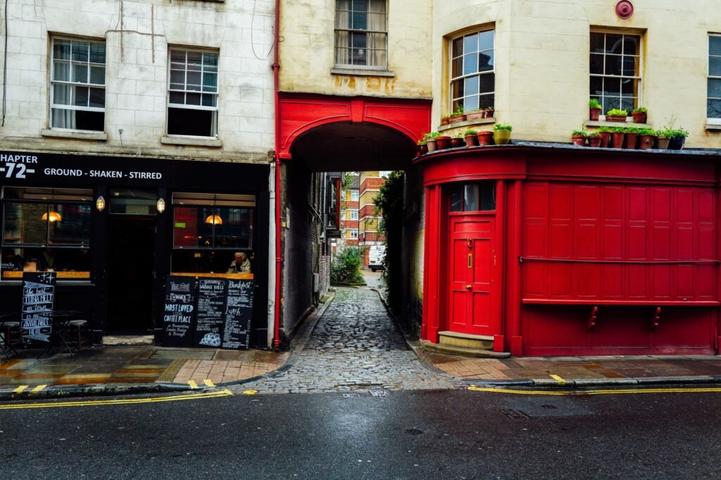 Quaint cobblestone street between two buildings with a cafe and vibrant red facade.