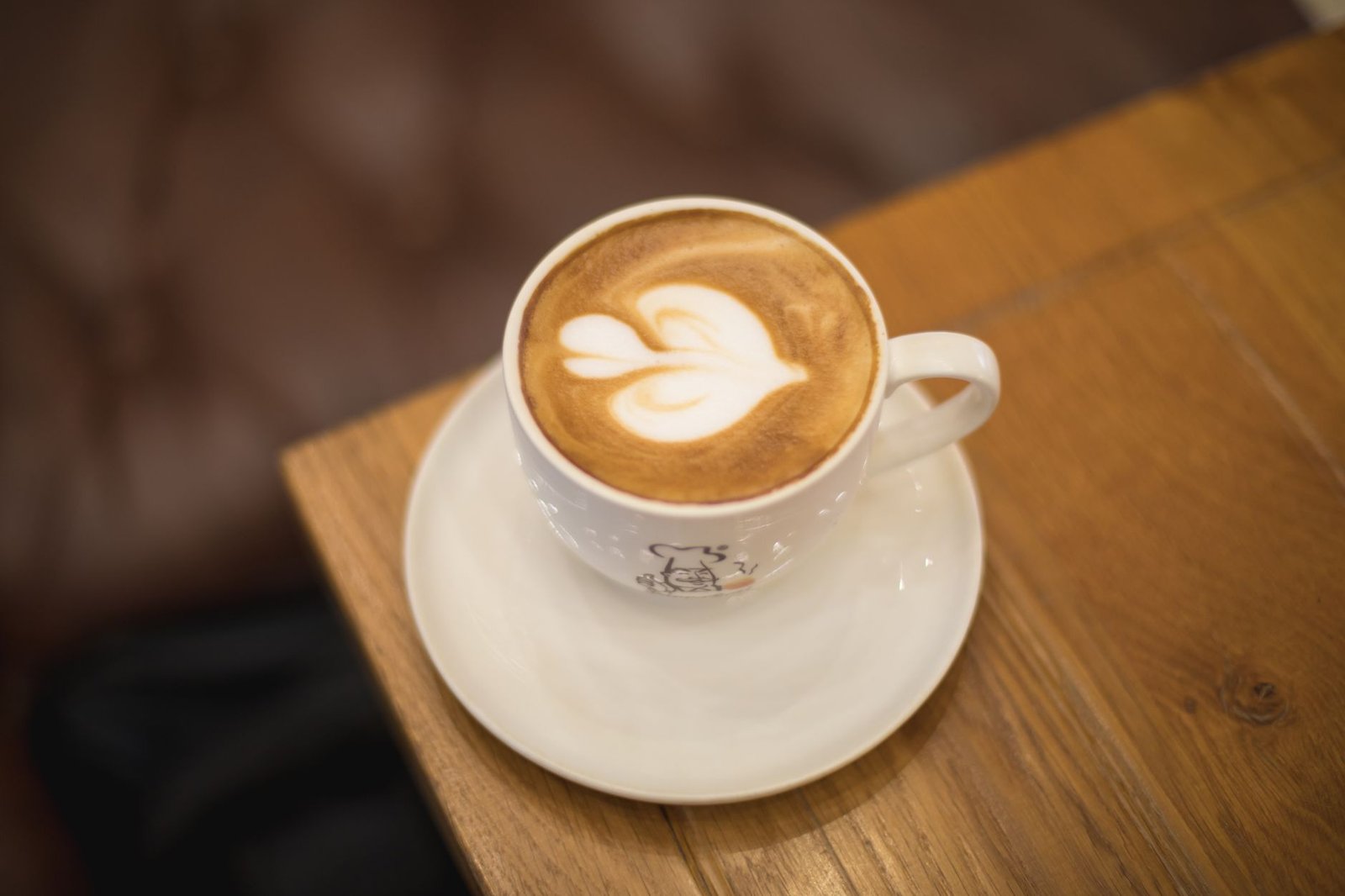 Top view of a latte art coffee cup on a wooden table in a cozy Dubai café.