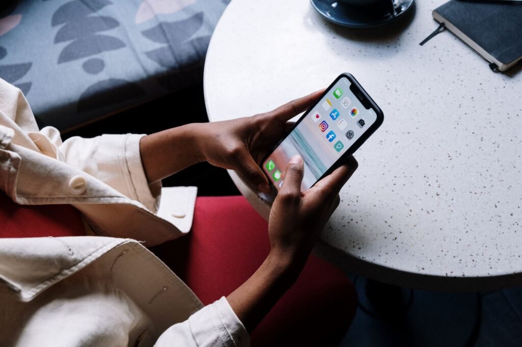 A person checks social media apps on a smartphone while sitting at a café table.