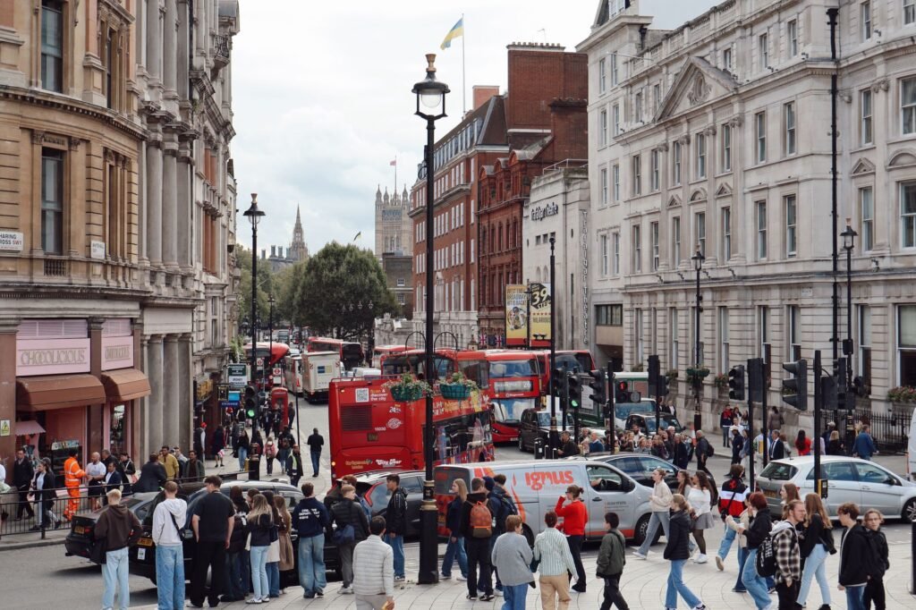 A bustling London street filled with people and iconic red buses, showcasing urban life in the city.