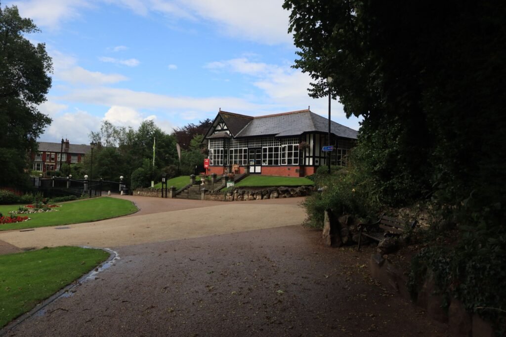 Beautiful park scene in Cheshire with a traditional English building and lush greenery.